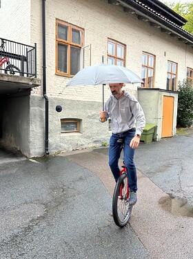 Man on a unicycle with an umbrella