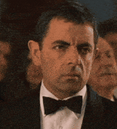 a man in a tuxedo and bow tie is looking at something